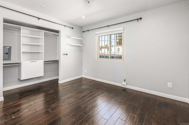 unfurnished bedroom featuring dark hardwood / wood-style floors, electric panel, and a closet