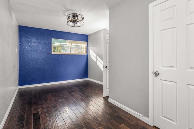 unfurnished room featuring a notable chandelier and dark hardwood / wood-style floors