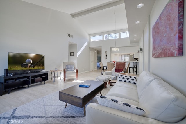 living room featuring high vaulted ceiling, light wood-type flooring, and beam ceiling