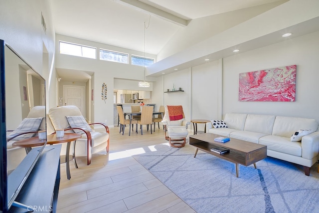 living room with beamed ceiling, high vaulted ceiling, and light hardwood / wood-style flooring