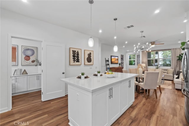 kitchen with hanging light fixtures, hardwood / wood-style floors, a notable chandelier, white cabinets, and a kitchen island