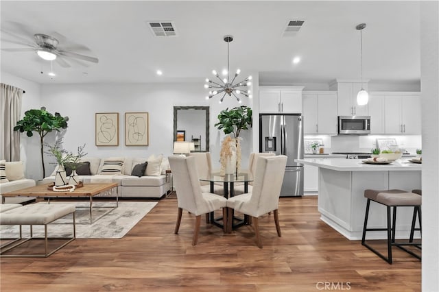 dining room featuring wood-type flooring and ceiling fan with notable chandelier