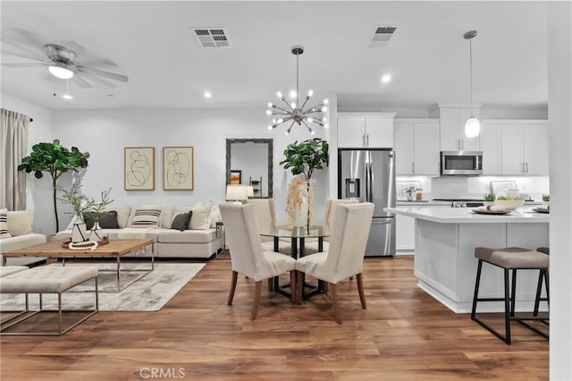 dining room with hardwood / wood-style flooring and ceiling fan with notable chandelier