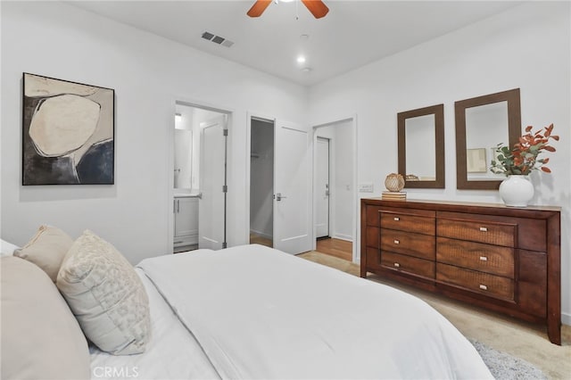 bedroom featuring light carpet, a spacious closet, ceiling fan, and ensuite bathroom