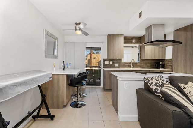 kitchen with extractor fan, light tile patterned flooring, a breakfast bar area, backsplash, and kitchen peninsula