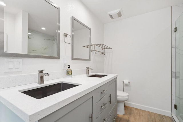 bathroom featuring wood-type flooring, toilet, an enclosed shower, and vanity