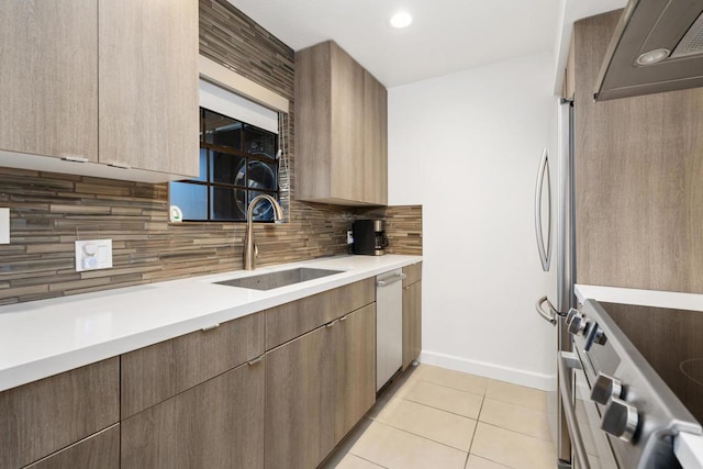 kitchen with sink, light tile patterned floors, appliances with stainless steel finishes, decorative backsplash, and wall chimney exhaust hood