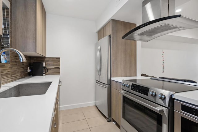 kitchen with sink, stainless steel appliances, island range hood, light tile patterned flooring, and decorative backsplash