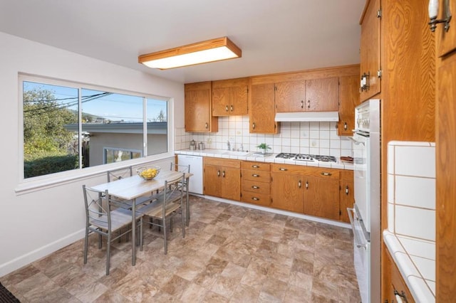 kitchen with tile countertops, sink, decorative backsplash, white dishwasher, and gas stovetop