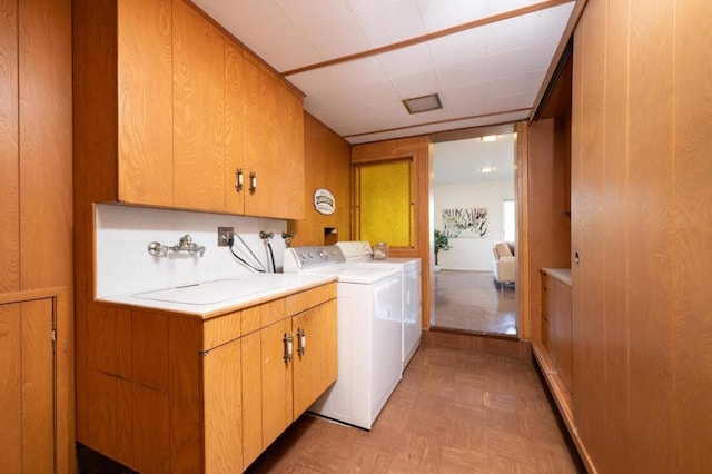 clothes washing area with cabinets, washer and clothes dryer, sink, and light parquet floors