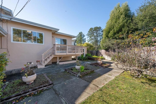 back of house featuring a wooden deck and a patio