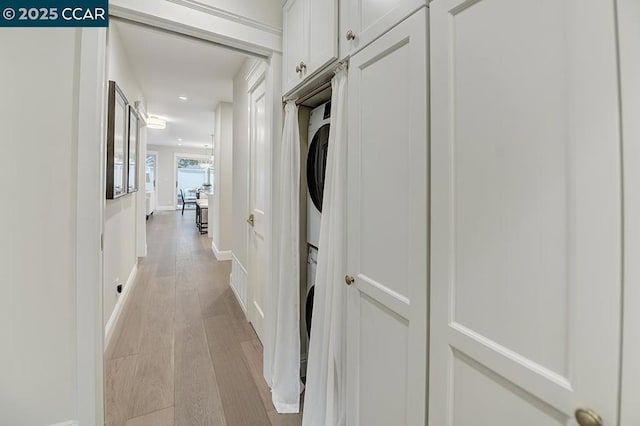 hallway with stacked washer and dryer and light hardwood / wood-style floors