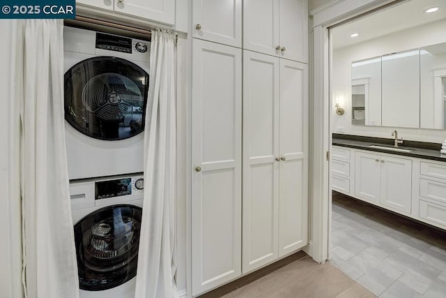 clothes washing area featuring stacked washing maching and dryer and sink