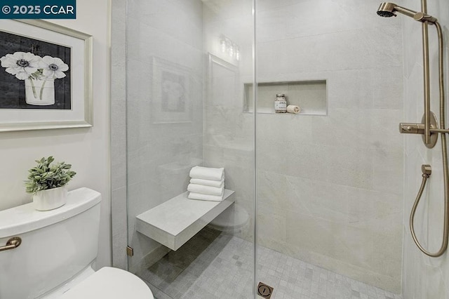 bathroom featuring tiled shower and toilet