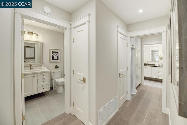 hall with sink and light wood-type flooring