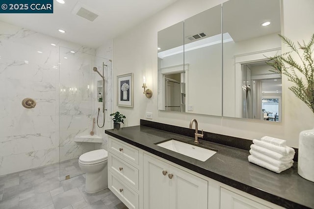 bathroom with vanity, toilet, and a tile shower