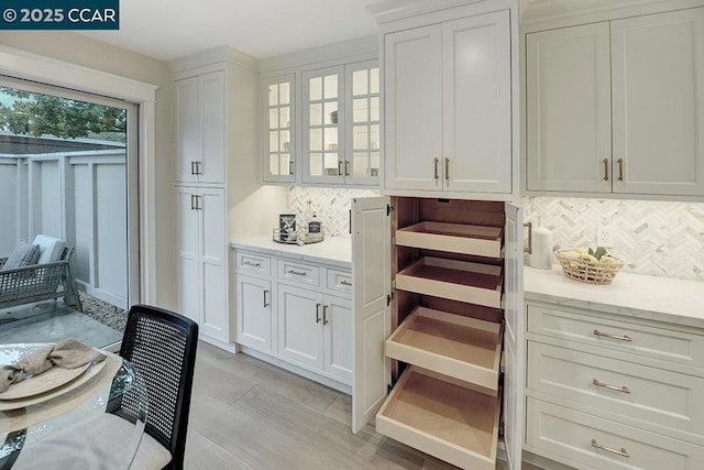 bar with white cabinetry, light stone countertops, and backsplash