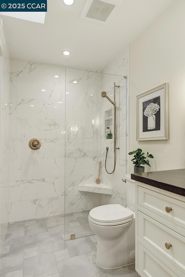 bathroom with a tile shower, vanity, and toilet