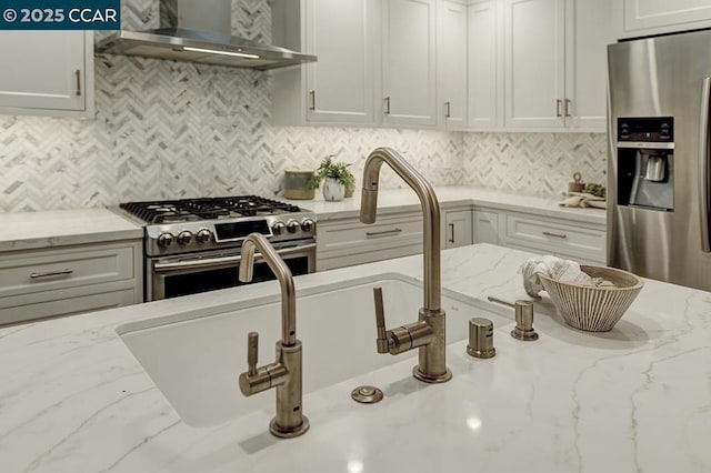 kitchen featuring wall chimney exhaust hood, appliances with stainless steel finishes, light stone countertops, and backsplash