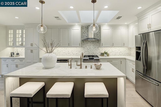 kitchen with stainless steel appliances, white cabinets, and wall chimney exhaust hood