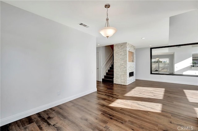 unfurnished living room with dark hardwood / wood-style flooring and a stone fireplace