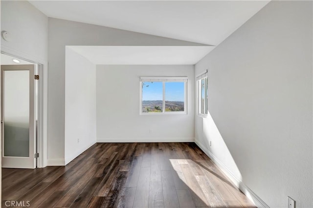 spare room with dark wood-type flooring and vaulted ceiling