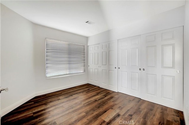 unfurnished bedroom with a closet and dark hardwood / wood-style floors