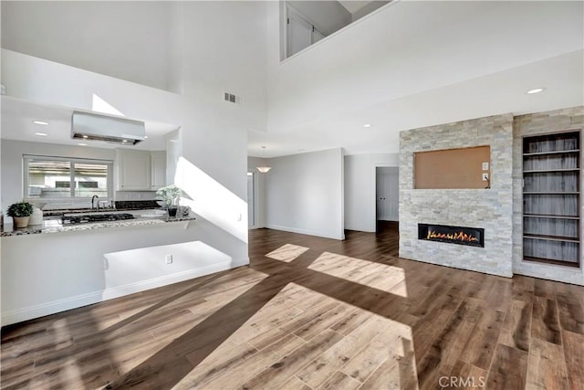 unfurnished living room featuring a fireplace, dark hardwood / wood-style flooring, and a towering ceiling