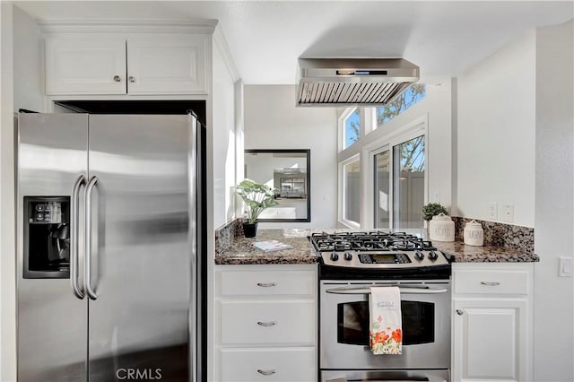 kitchen featuring white cabinetry, stainless steel appliances, and dark stone countertops