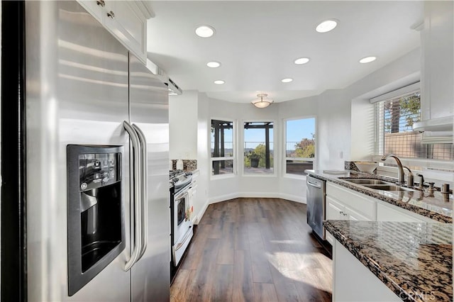 kitchen with white cabinetry, sink, stainless steel appliances, and dark stone countertops