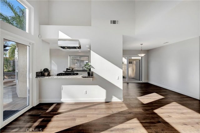 interior space with dark wood-type flooring, a towering ceiling, and a wall unit AC