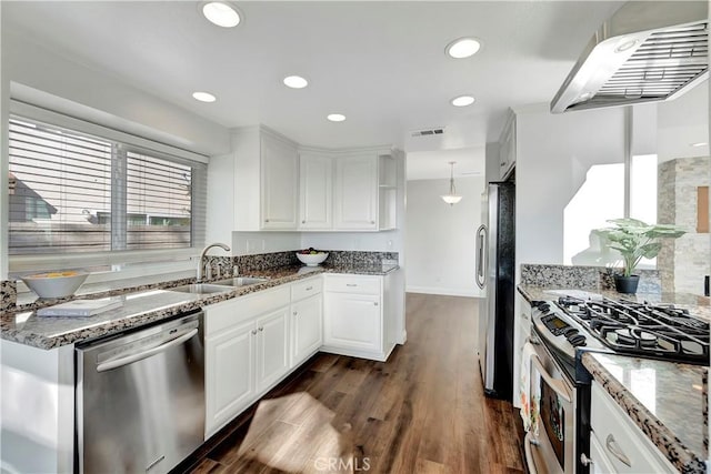 kitchen featuring sink, decorative light fixtures, dark stone countertops, appliances with stainless steel finishes, and white cabinets