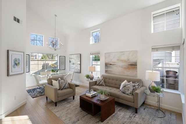 living room featuring an inviting chandelier, high vaulted ceiling, and light hardwood / wood-style floors