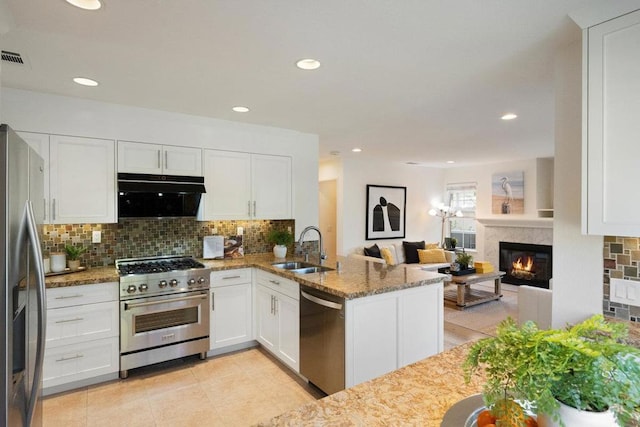 kitchen featuring appliances with stainless steel finishes, stone countertops, sink, white cabinets, and kitchen peninsula