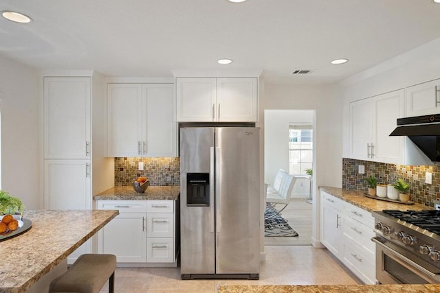 kitchen with white cabinetry, stainless steel appliances, light stone counters, and backsplash