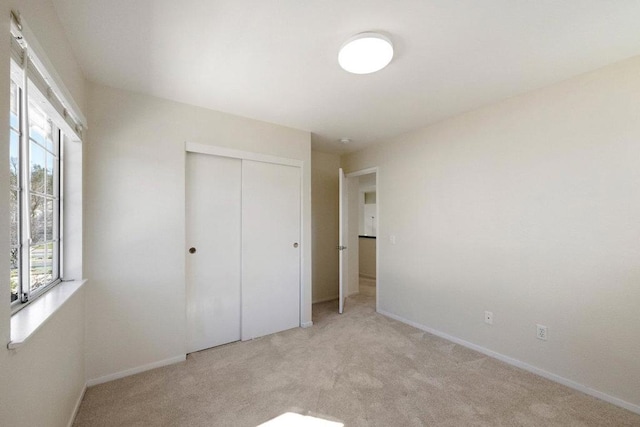 unfurnished bedroom featuring light colored carpet and a closet