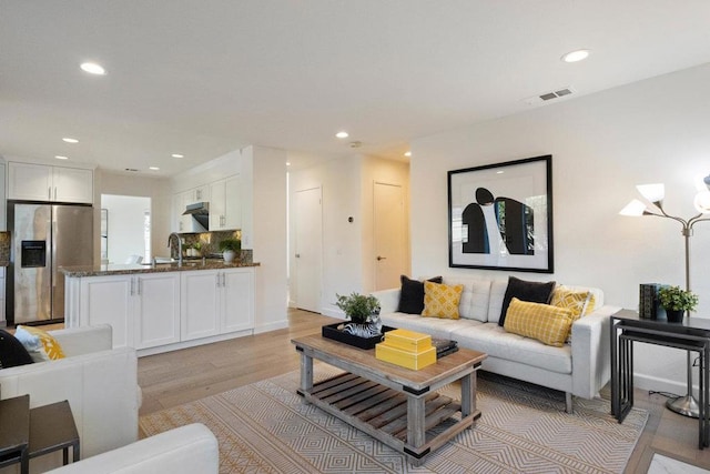 living room featuring sink and light hardwood / wood-style flooring