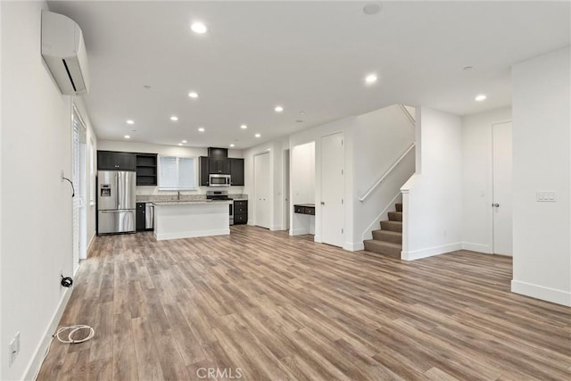 unfurnished living room with wood-type flooring and a wall mounted air conditioner