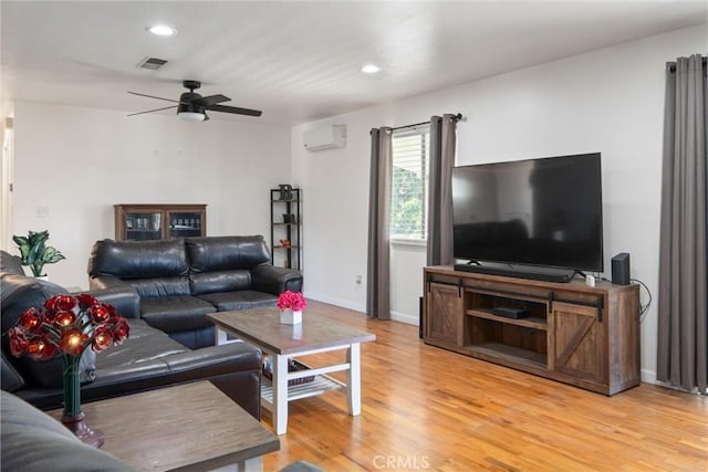 living room featuring ceiling fan, light hardwood / wood-style floors, and a wall mounted AC