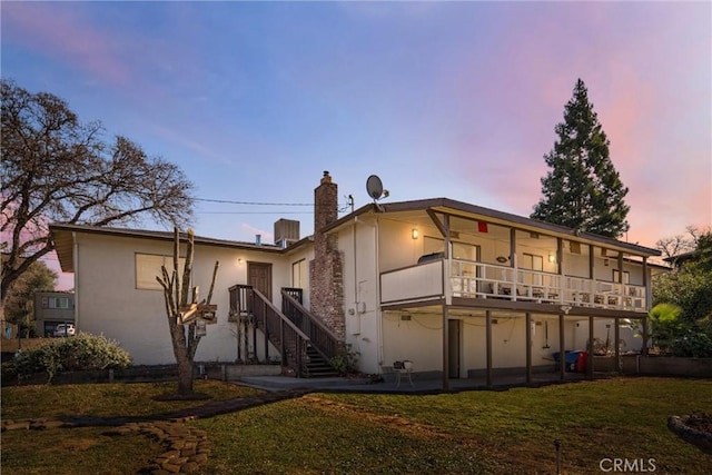 back house at dusk featuring a yard