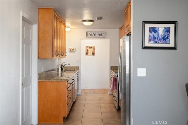 kitchen featuring light stone counters, sink, light tile patterned floors, and appliances with stainless steel finishes