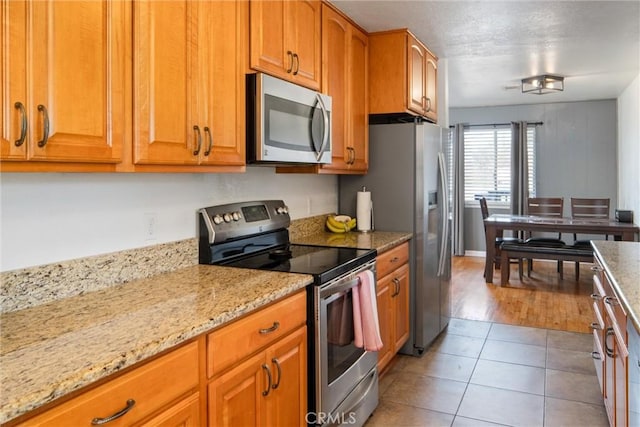 kitchen featuring light stone counters, light tile patterned floors, and appliances with stainless steel finishes