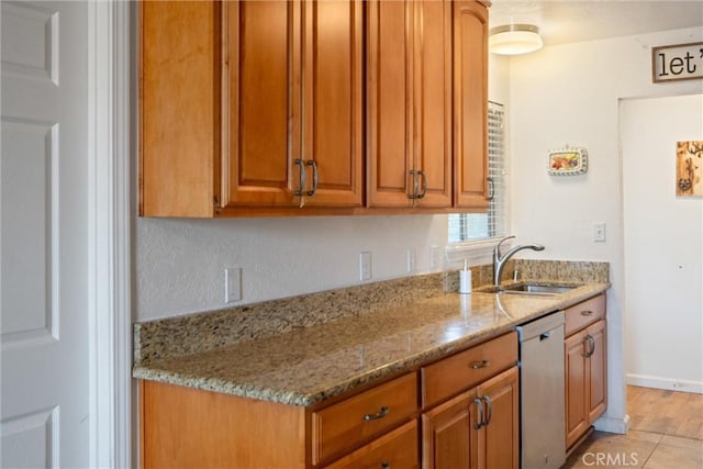 kitchen featuring light stone counters, dishwasher, and sink