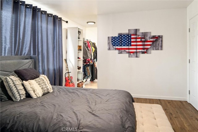 bedroom featuring a walk in closet, wood-type flooring, and a closet