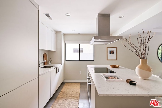 kitchen featuring sink, white cabinets, island exhaust hood, light stone countertops, and black electric cooktop