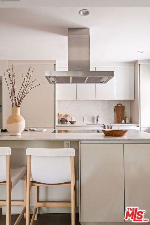 kitchen featuring white cabinetry, island range hood, and decorative backsplash