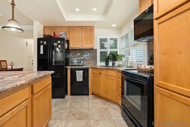 kitchen with sink, light stone counters, black appliances, a raised ceiling, and backsplash