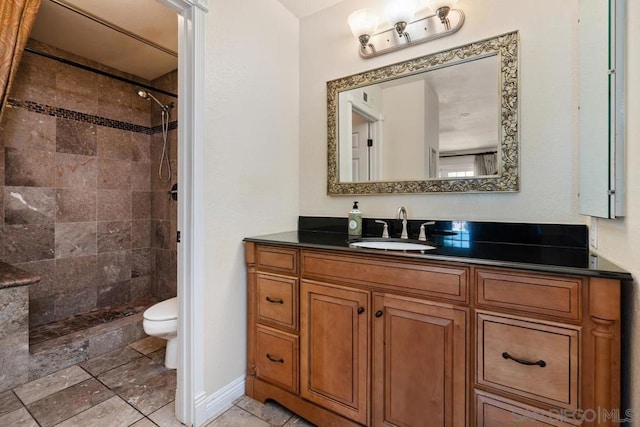 bathroom featuring tiled shower, vanity, and toilet