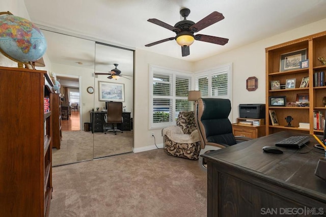 office featuring light carpet, ceiling fan, and a healthy amount of sunlight