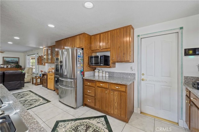 kitchen featuring stainless steel appliances, light tile patterned floors, and light stone counters